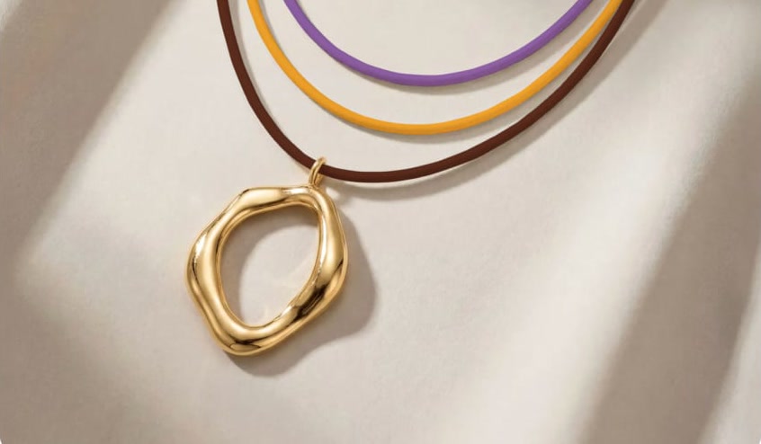 A gold pendant on three cords of different colors